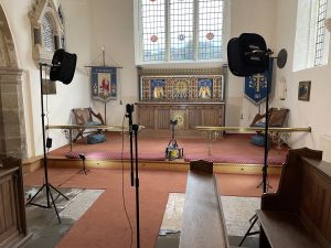 A church chancel with video lights and a camera setup for filming.