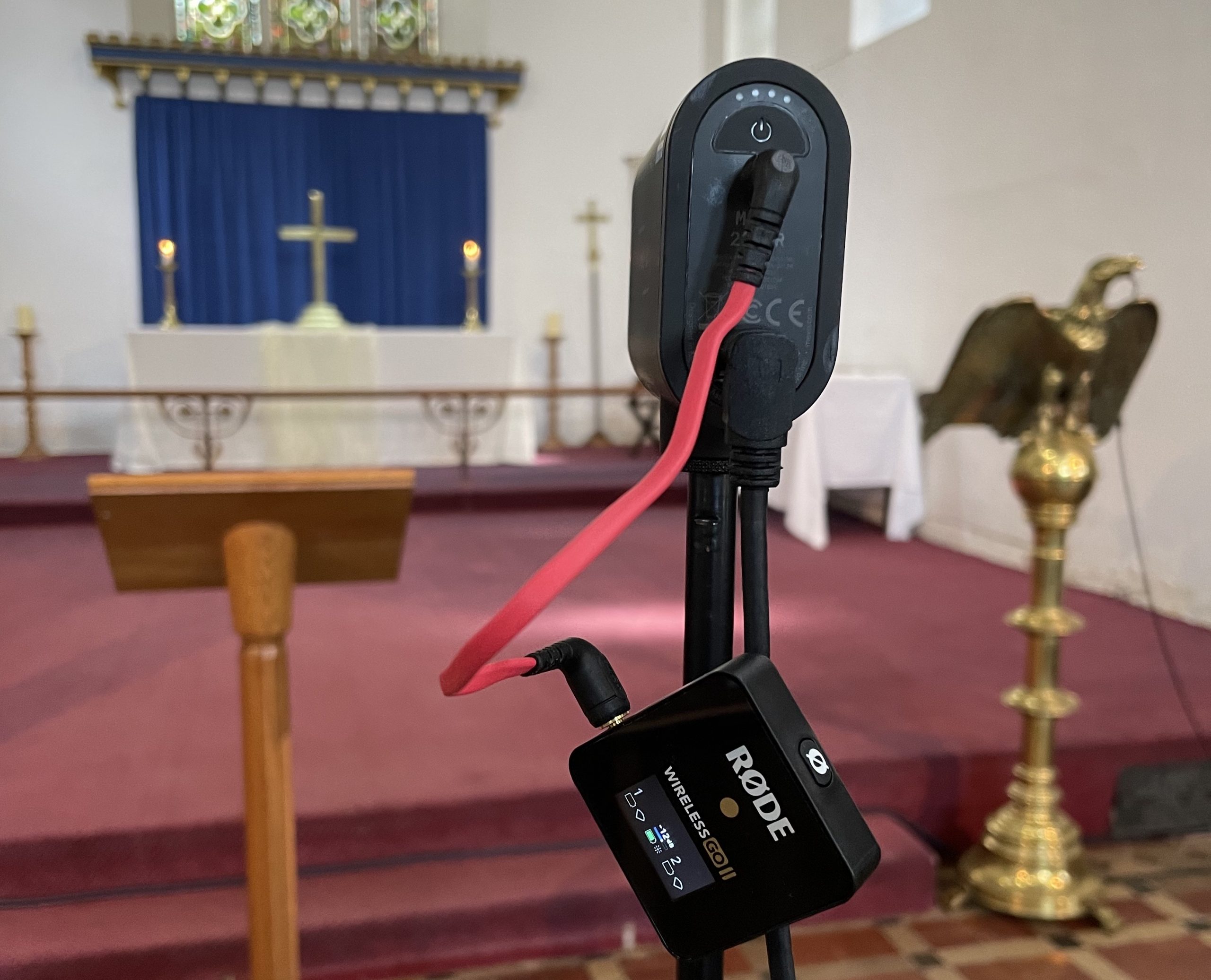 A Mevo Start Camera with a Rode Wireless Go receiver pointing at the front of an anglican church with a cross on the communion table.